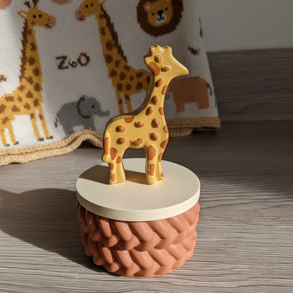 Painted golden yellow giraffe trinket box with terracotta base in nursery scene with zoo animal blanket