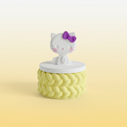 Painted cartoon cat figure trinket box with purple bow and lemon base on lemon and cream background