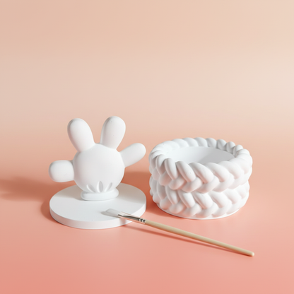 White plaster cartoon hand trinket box with paintbrush on warm peach coral background
